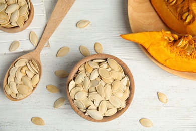 Photo of Flat lay composition with raw pumpkin seeds on white wooden table