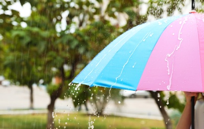 Photo of Person with bright umbrella under rain on street, closeup