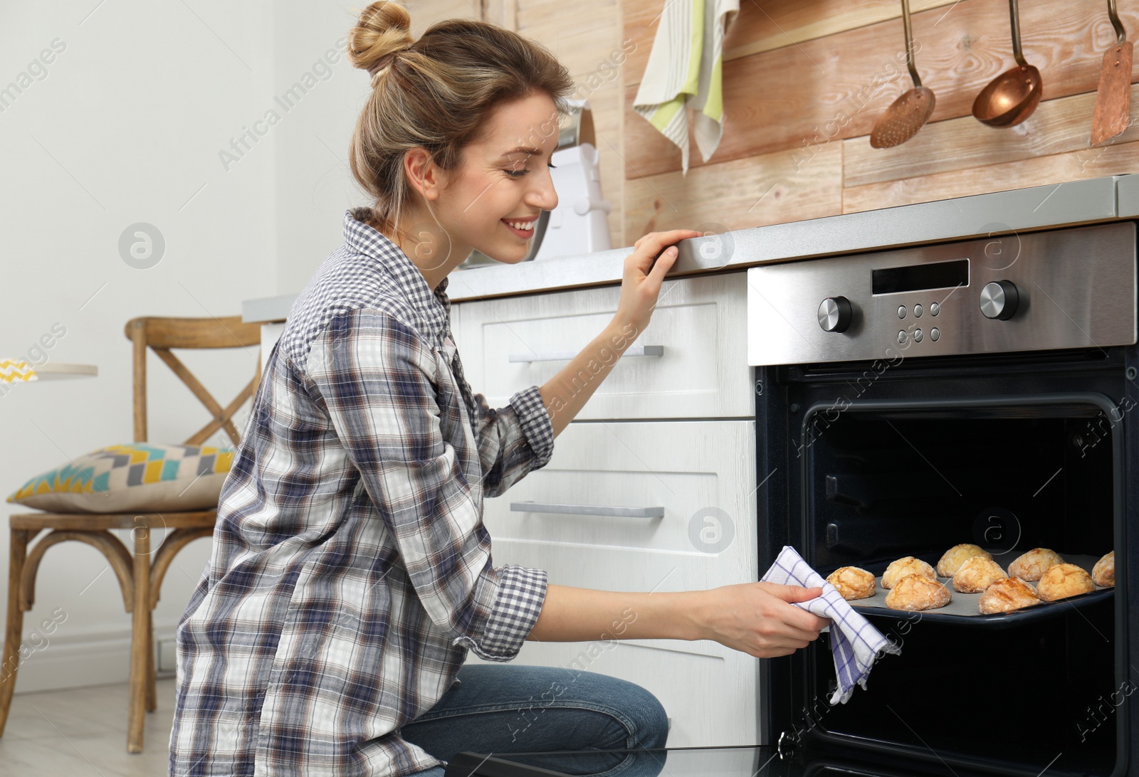 Photo of Young woman baking cookies in oven at home