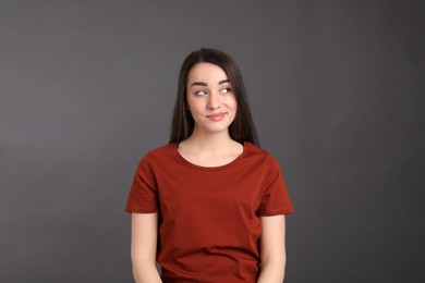 Photo of Portrait of happy young woman on dark grey background. Personality concept