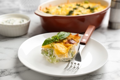 Photo of Piece of tasty broccoli casserole on white marble table