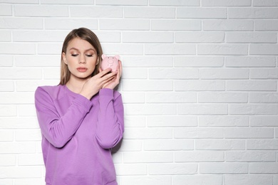 Photo of Young woman with piggy bank on brick wall background. Space for text