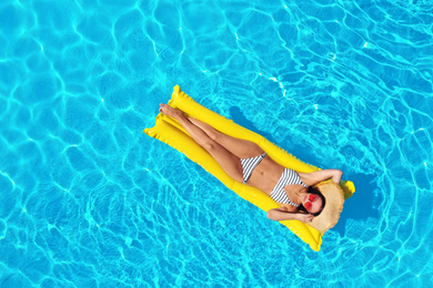 Image of Young woman with inflatable mattress in swimming pool, top view