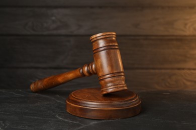 Photo of Wooden gavel on dark textured table, closeup