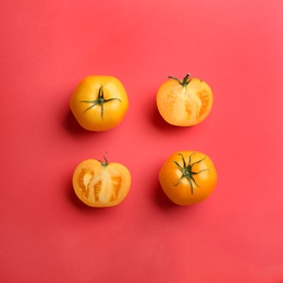 Photo of Yellow tomatoes on red background, flat lay