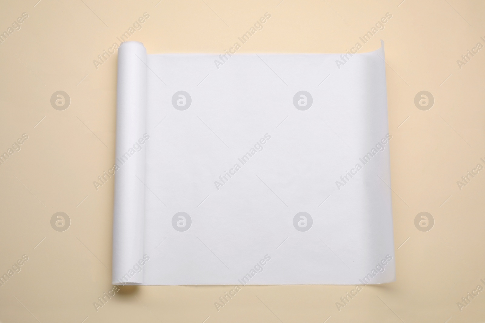 Photo of Roll of baking paper on beige background, top view