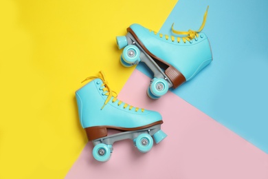 Photo of Pair of stylish quad roller skates on color background, top view