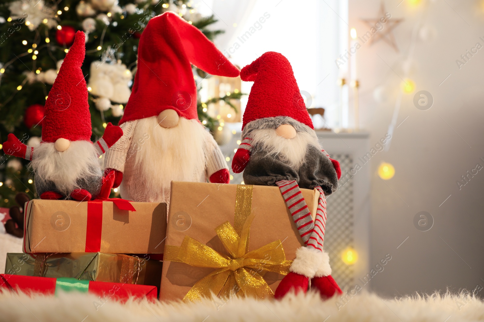 Photo of Cute Christmas gnomes and gift boxes on carpet in room