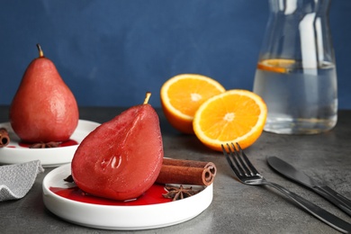 Photo of Plates with red wine poached pears and spices served on grey table