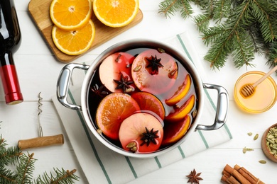 Delicious mulled wine and ingredients on white wooden table, flat lay