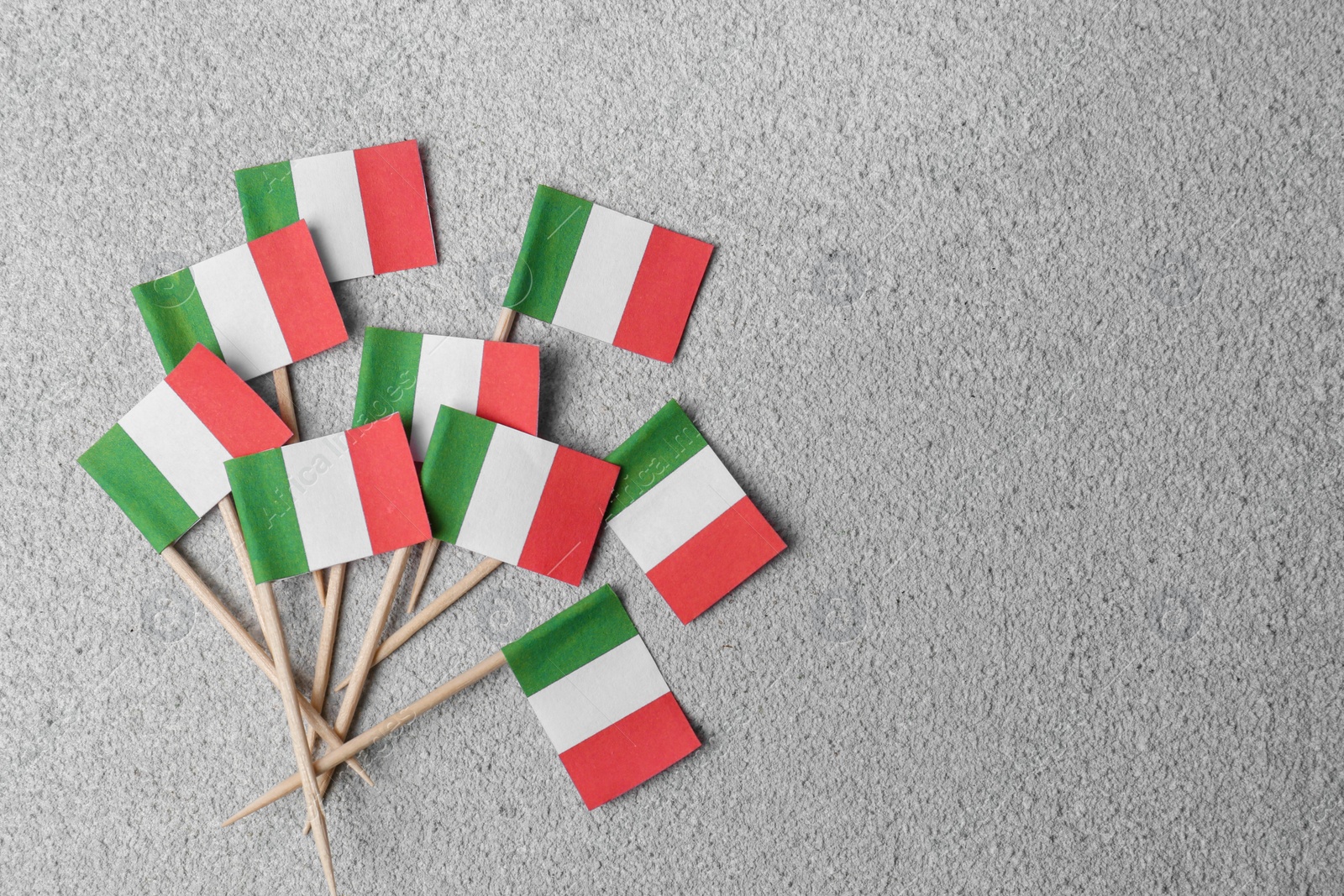 Photo of Small paper flags of Italy on grey textured table, flat lay. Space for text