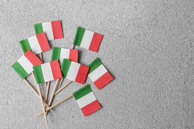 Photo of Small paper flags of Italy on grey textured table, flat lay. Space for text