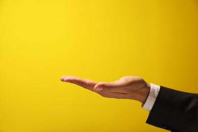 Photo of Man holding something in hand on yellow background, closeup. Space for text