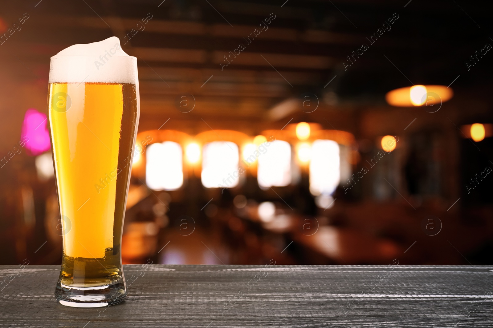 Image of Fresh cold beer on wooden table in pub, space for text