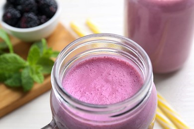 Mason jar of blackberry smoothie on white table, closeup