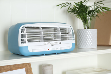 Photo of Modern air purifier on white wooden shelf, closeup