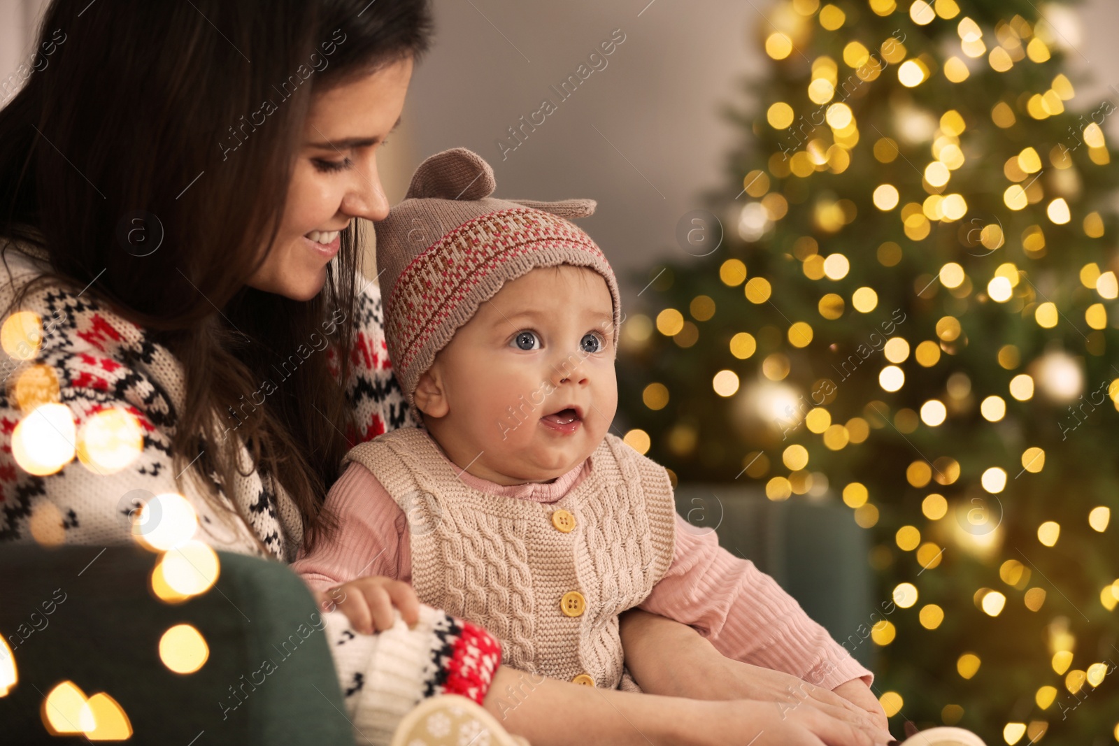 Photo of Happy young mother with her cute baby in room decorated for Christmas. Winter holiday