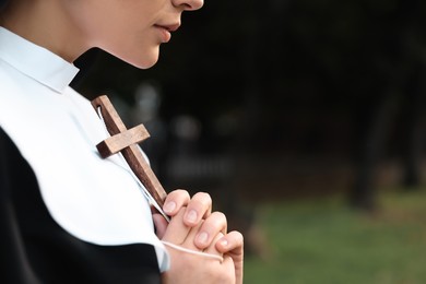 Photo of Young nun with Christian cross in park outdoors, closeup. Space for text