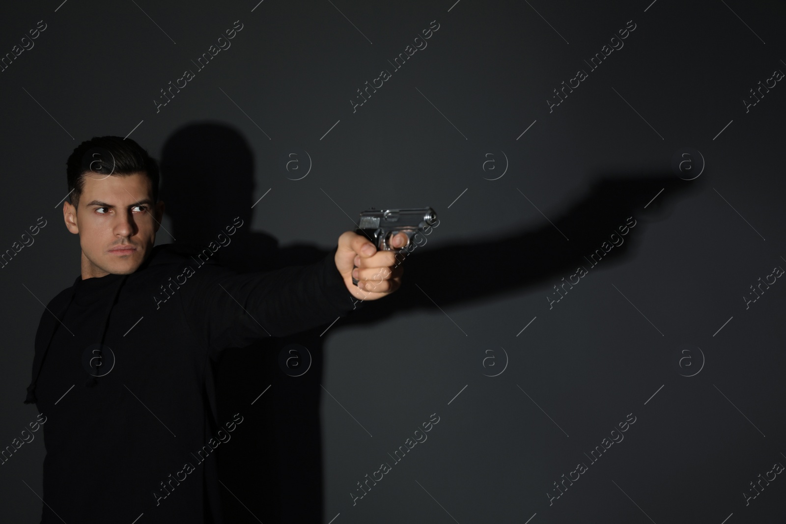 Photo of Professional killer with gun on black background