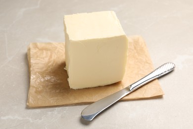 Block of tasty butter and knife on light table