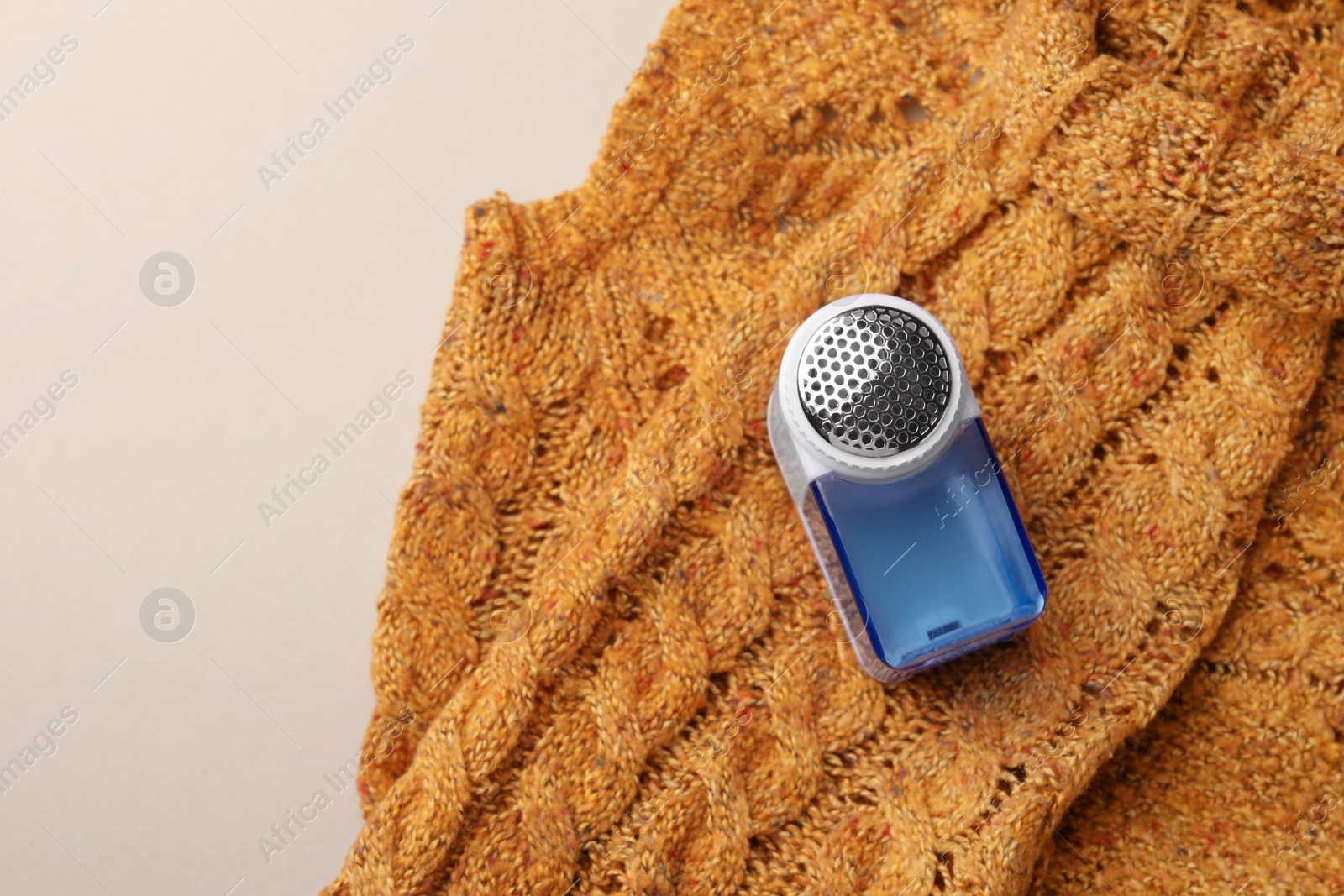 Photo of Modern fabric shaver and knitted sweater on white background, top view. Space for text