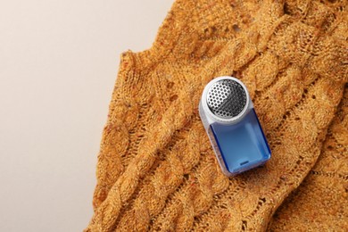 Photo of Modern fabric shaver and knitted sweater on white background, top view. Space for text