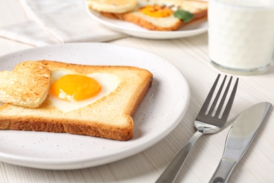 Tasty toast with fried egg served on white wooden table, closeup