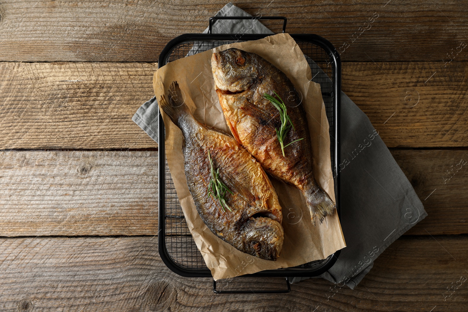 Photo of Delicious dorado fish with rosemary on wooden table, top view. Space for text