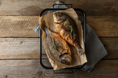 Photo of Delicious dorado fish with rosemary on wooden table, top view. Space for text