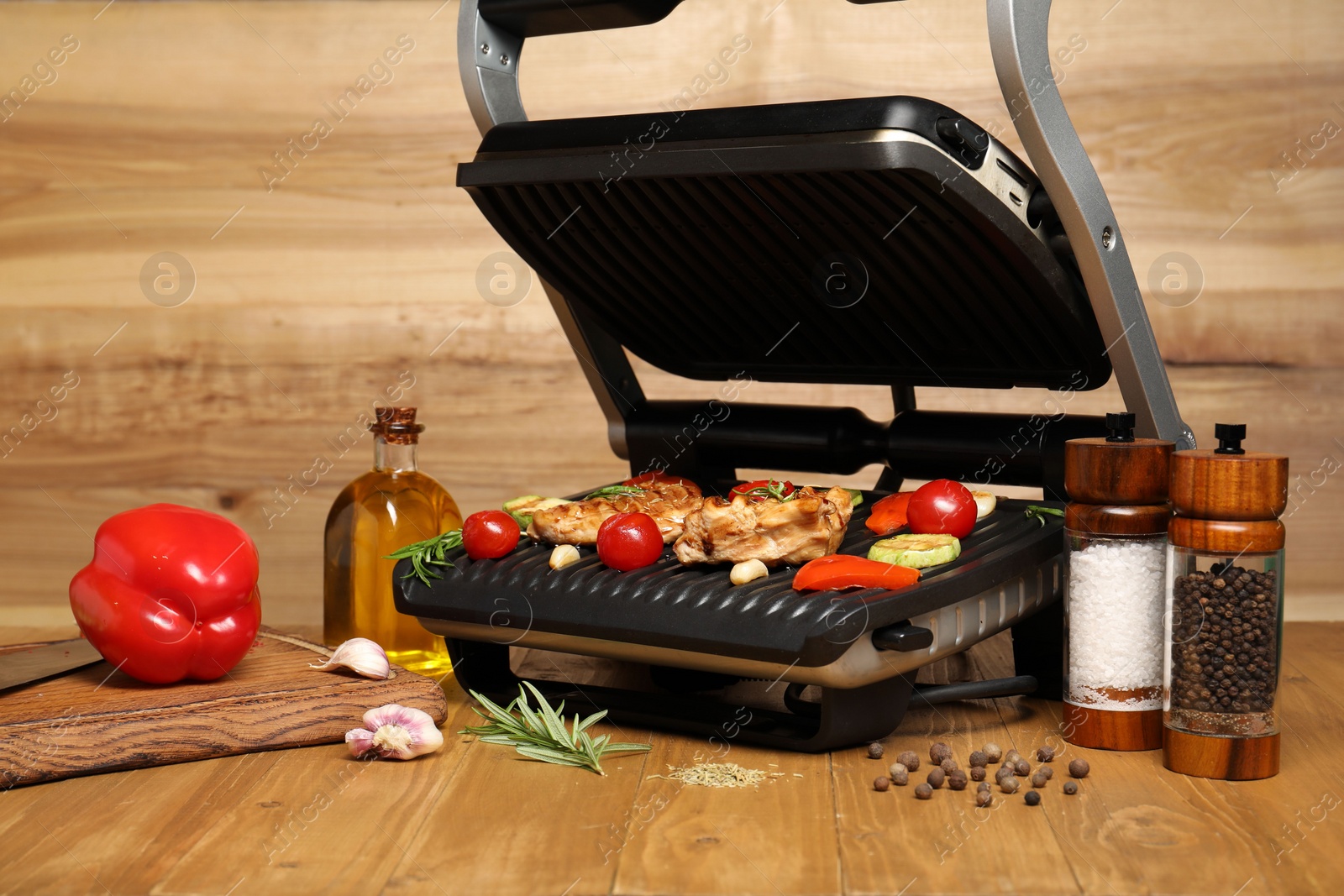 Photo of Electric grill with different products on wooden table