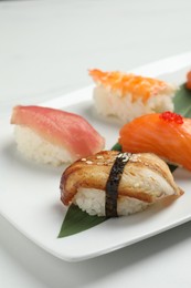 Plate with delicious nigiri sushi on white table, closeup