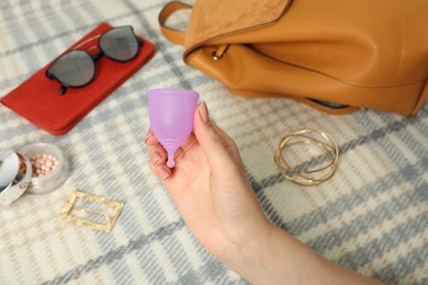 Photo of Woman holding violet menstrual cup over blanket, closeup