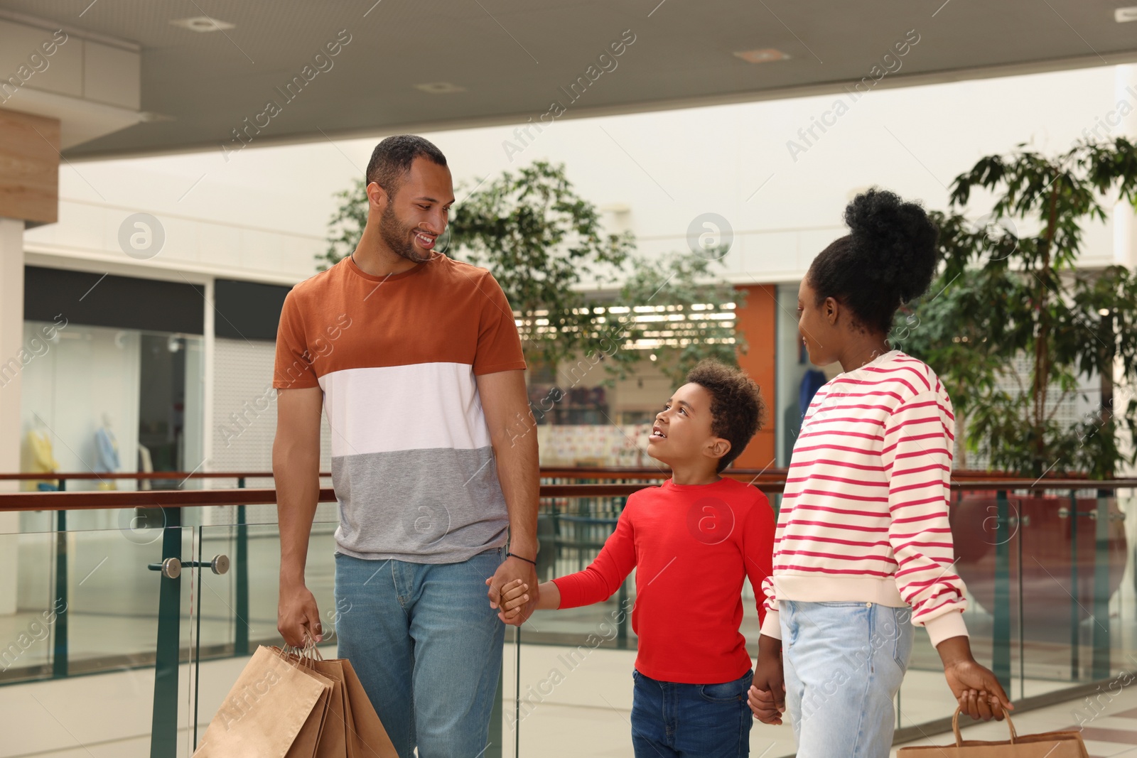 Photo of Family shopping. Happy parents and son with purchases in mall