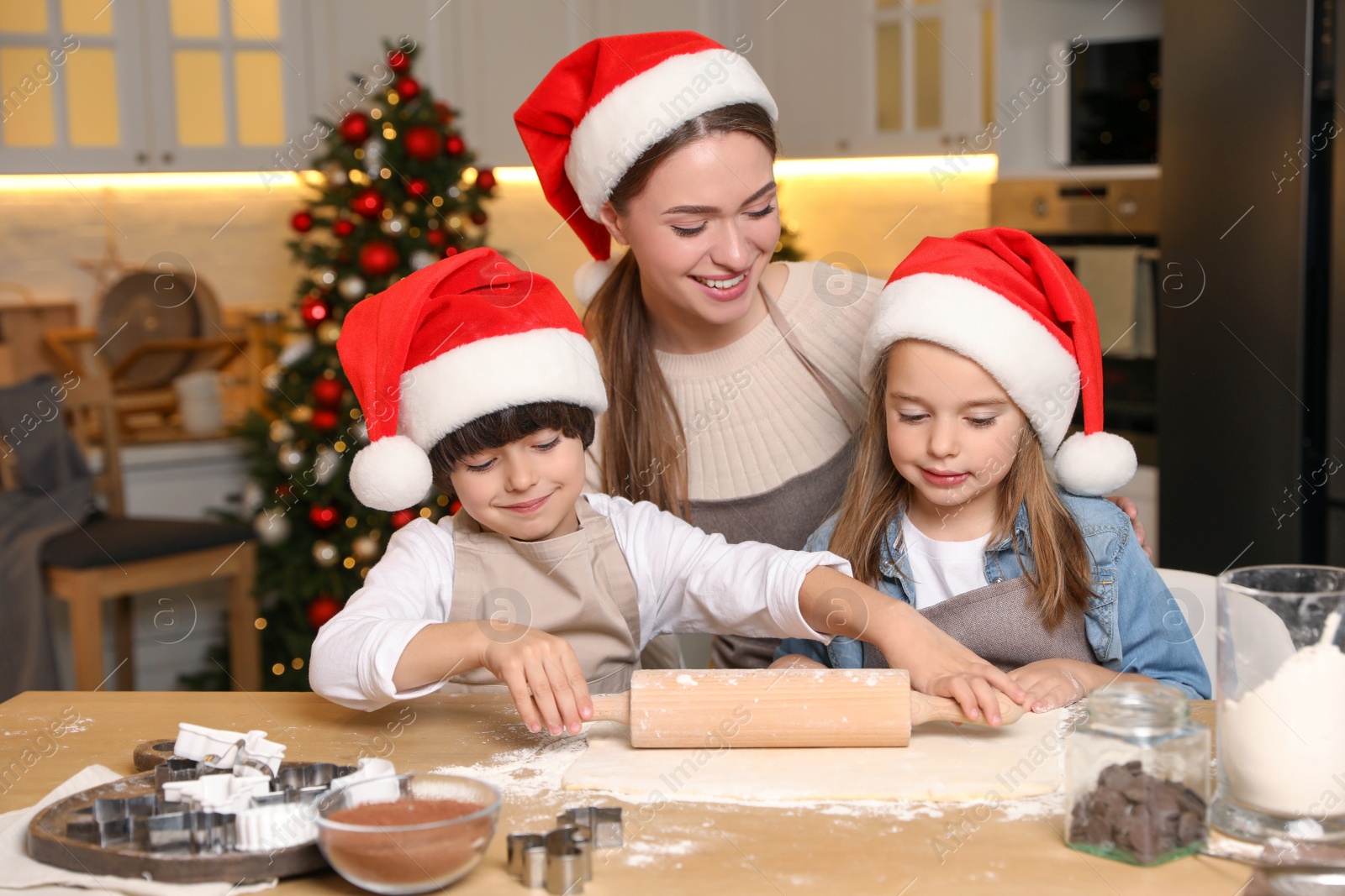 Photo of Mother with her cute little children making dough for Christmas cookies in kitchen