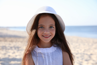Photo of Cute little child wearing hat at sandy beach on sunny day