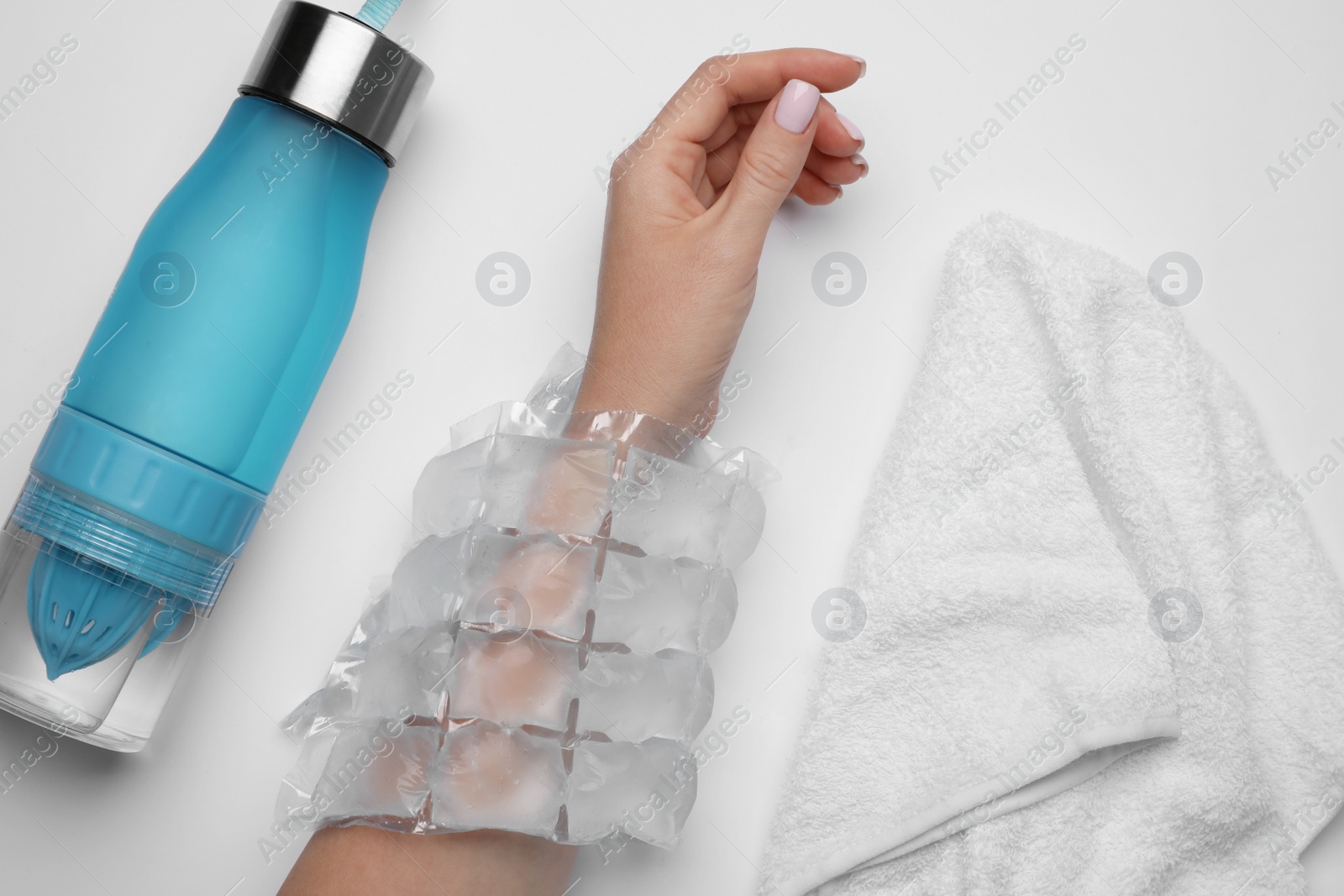 Photo of Woman with ice pack, bottle of water and towel on white background, top view. Heat stroke treatment