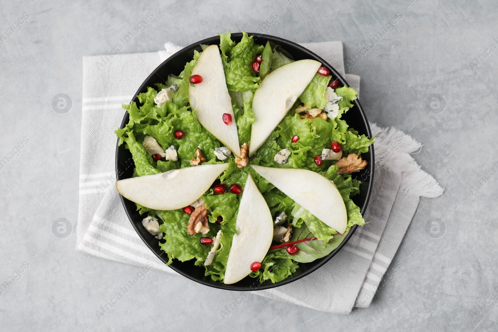 Photo of Delicious pear salad in bowl on grey textured table, top view