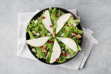 Photo of Delicious pear salad in bowl on grey textured table, top view