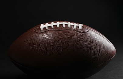 Photo of American football ball on black background, closeup