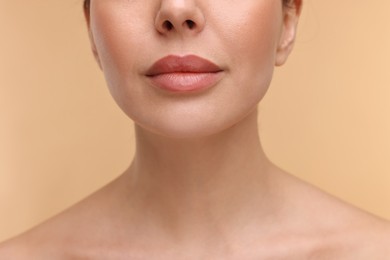 Woman with beautiful lips on beige background, closeup