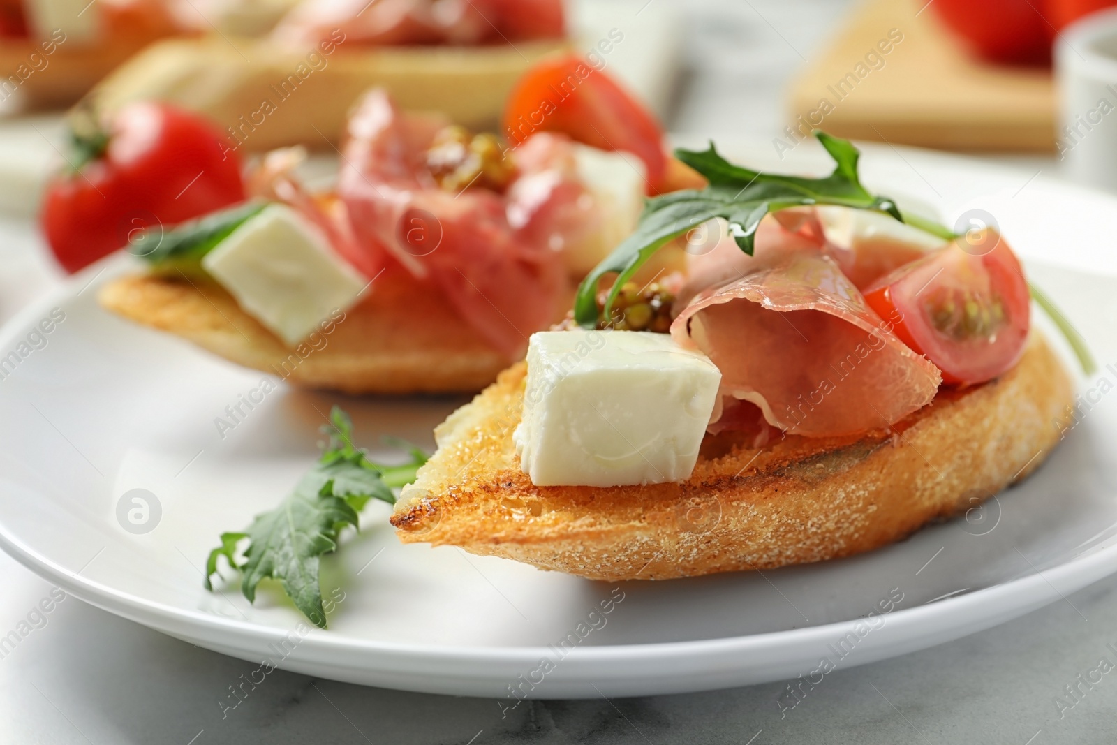 Photo of Plate of tasty bruschettas with prosciutto on table, closeup