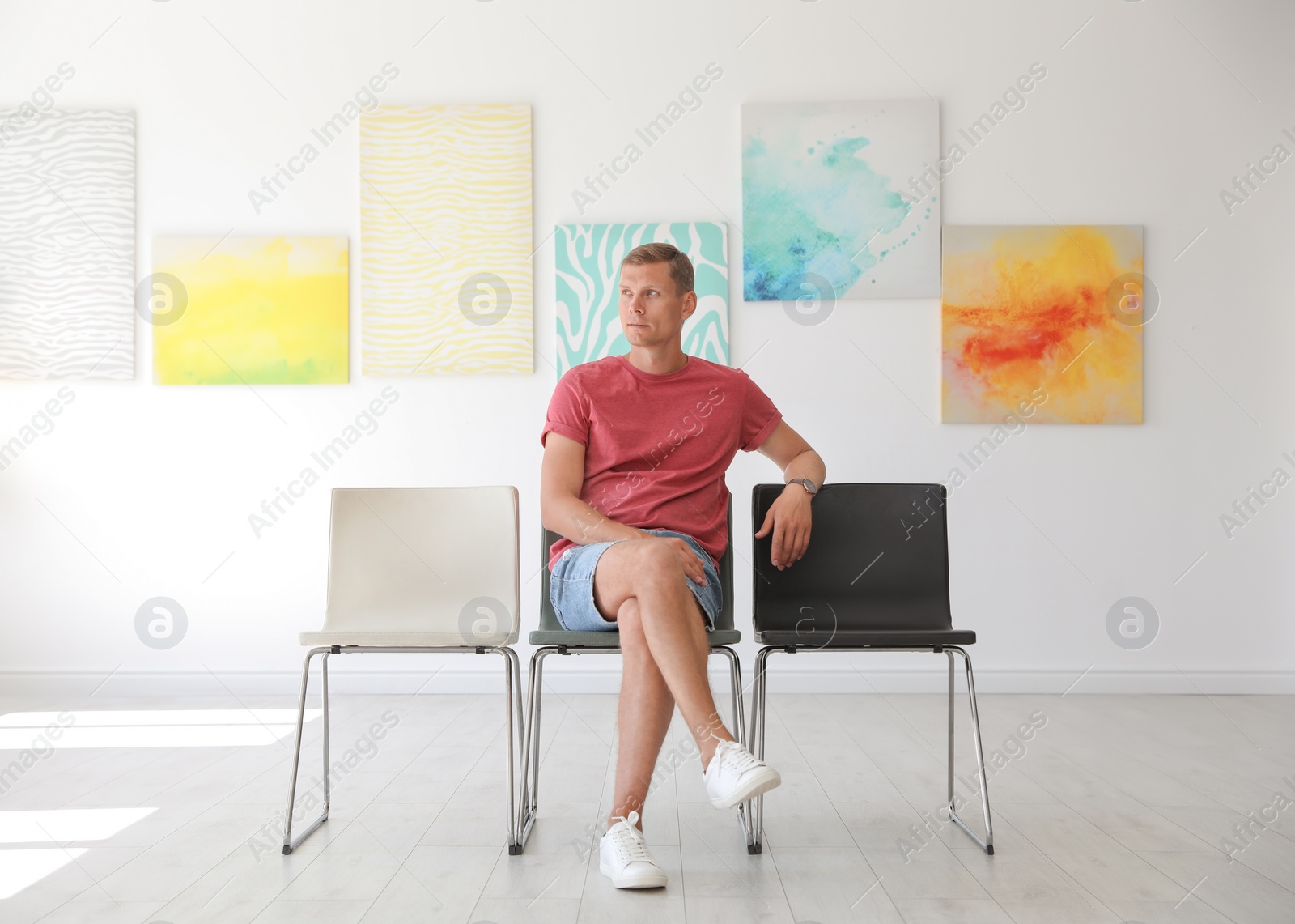 Photo of Young man sitting on chair at exhibition in art gallery