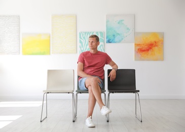 Young man sitting on chair at exhibition in art gallery