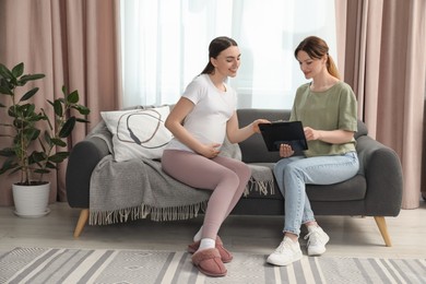 Doula working with pregnant woman on sofa at home. Preparation for child birth