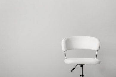 Photo of Comfortable office chair on light background. Space for text