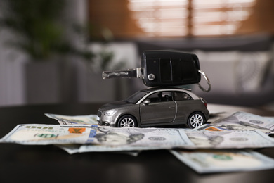 Miniature automobile model, key and money on table indoors. Car buying