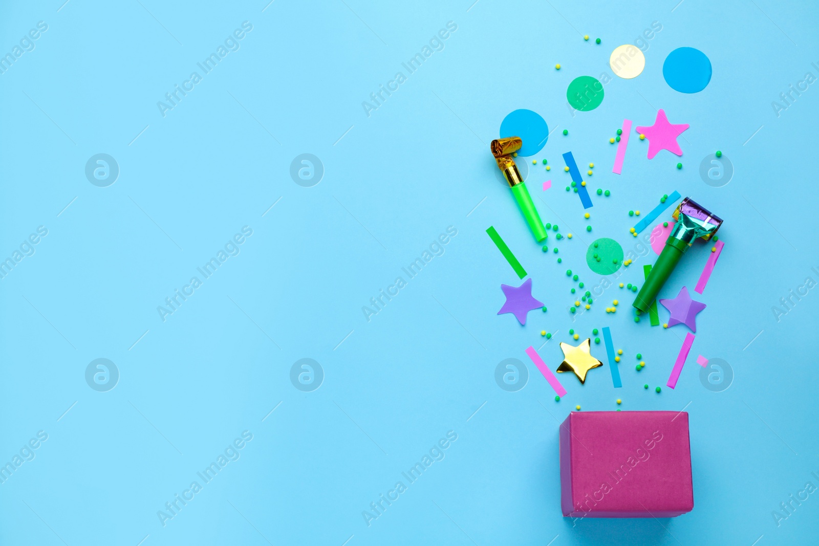 Photo of Party horns, confetti and box on light blue background, flat lay. Space for text