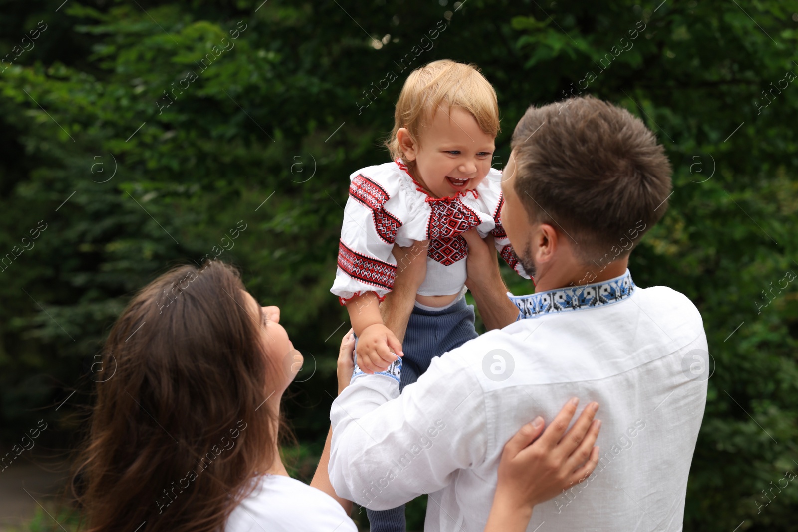 Photo of Happy family in Ukrainian national clothes outdoors