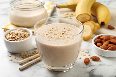 Photo of Glass of tasty banana smoothie with oatmeal on white marble table