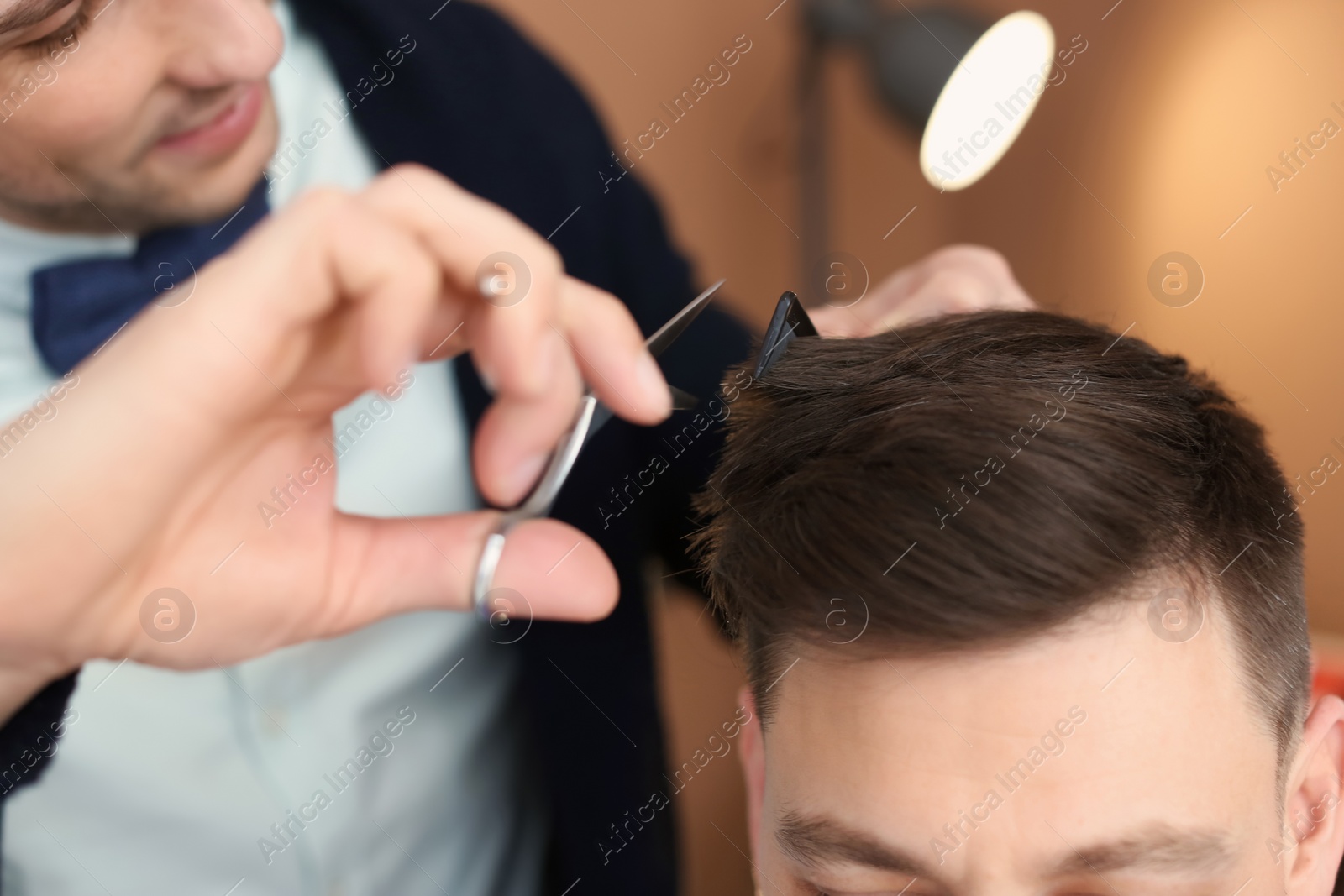 Photo of Professional hairdresser working with client in beauty salon, closeup